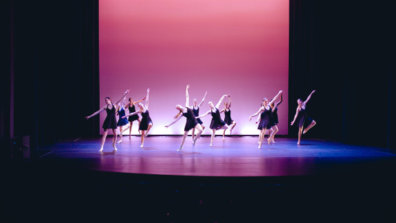 A group of dancers wearing black dresses on stage