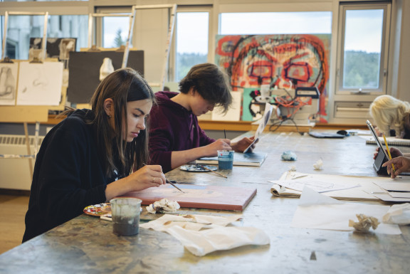 Two students painting at a desk