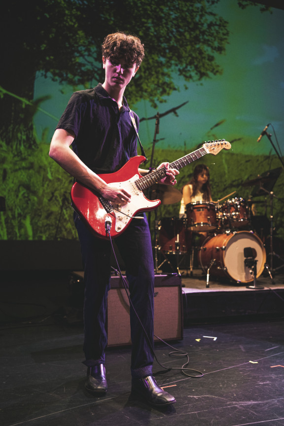 A student playing guitar with the rock band