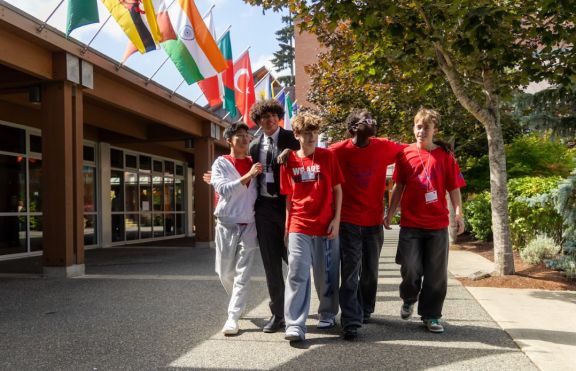 Private school students walking under international flags outside on Opening Day