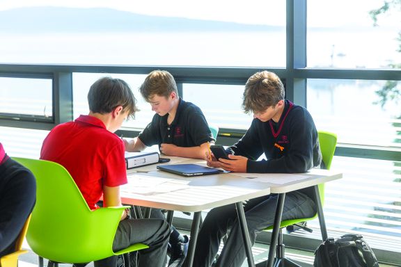 Three students study math in sunlit room
