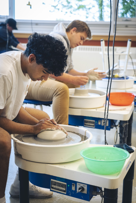 Two boys working on potting wheels in the studio