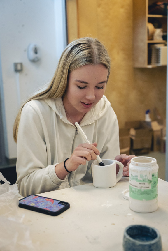 A student painting a new hand-built mug