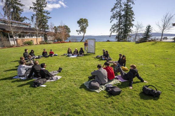 A class siting outside with the ocean in the background