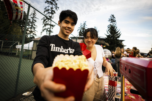 Two students handing out popcorn at a fun fair