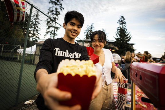Two private school students handing out popcorn at a fun fair