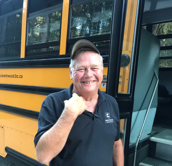 A bus driver smiling in front of a bus