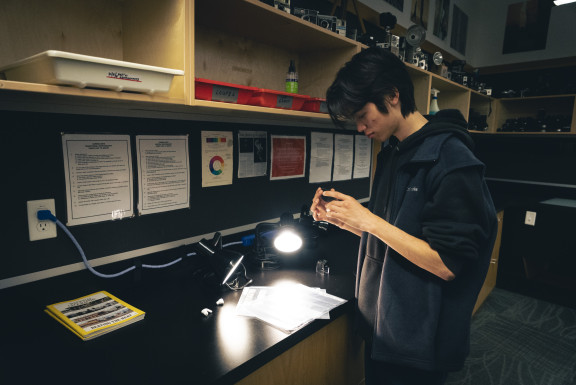 A student looks at a negative in the photography studio
