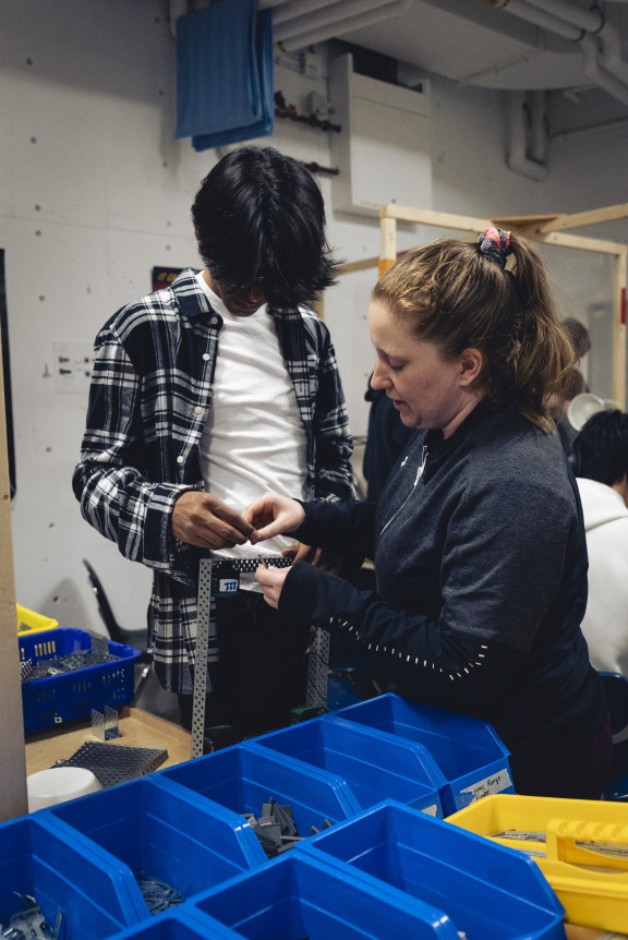 A teacher demonstrating the assembly of a robotics part