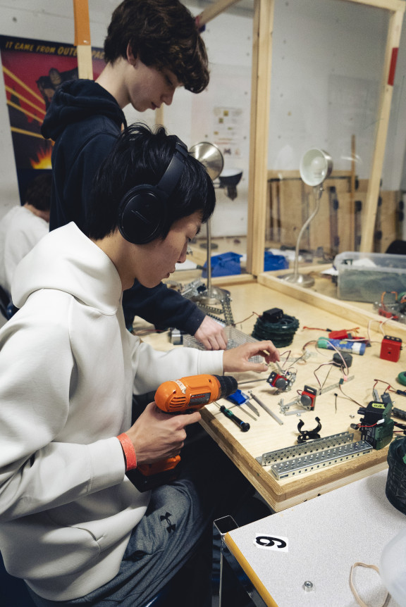 A student using a screw driver to build a robot