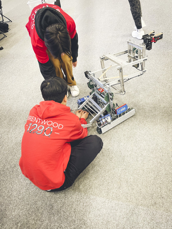 A student kneeling down to work on a robot