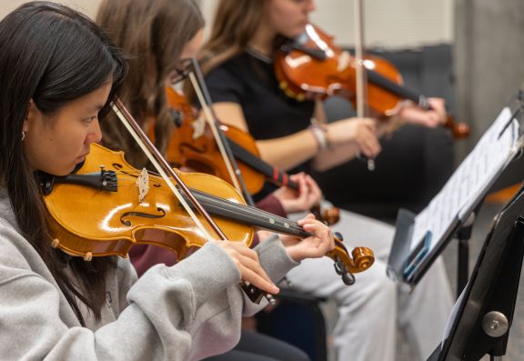 Students practicing violin in Asper Room