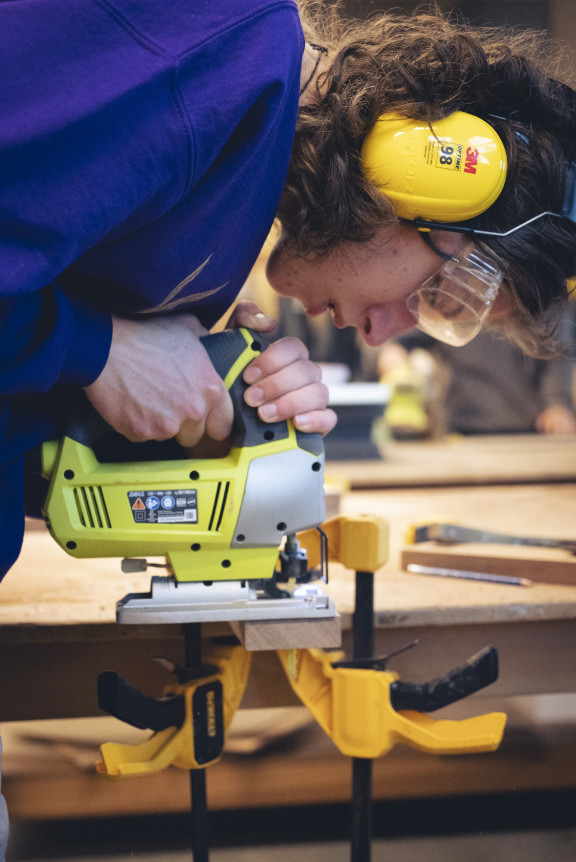 A student using a jigsaw to cut a piece of wood