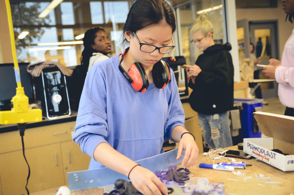 A student with ear protection working on sculpture