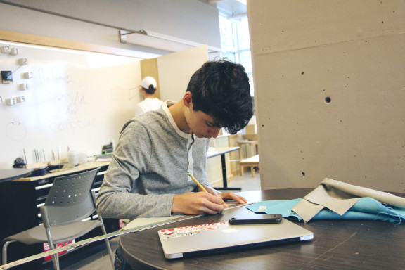 A students using a pencil to create a project in the studio