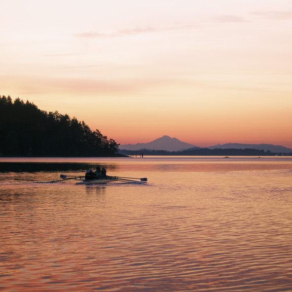 A rowing crew on the water during a morning sunrise