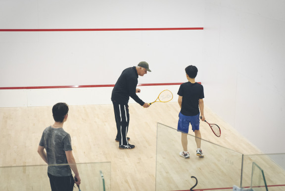 A coach instructing players on the proper squash technique