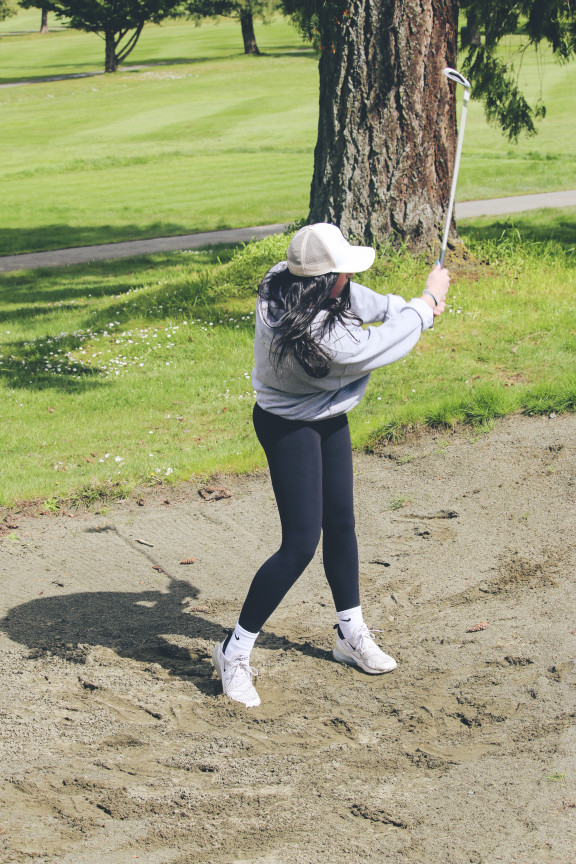A student hitting the ball out of the bunker