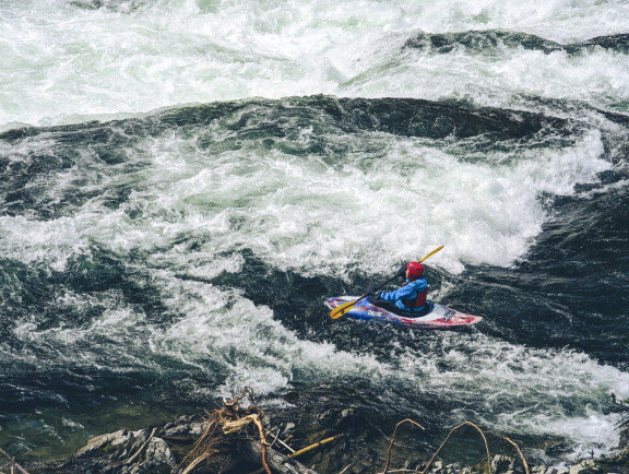 A students travelling through white water in a kayak