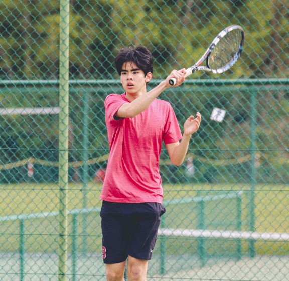 A student hitting a forehand tennis shot in practice