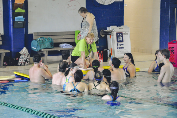 An instructor talking to students at a local pool