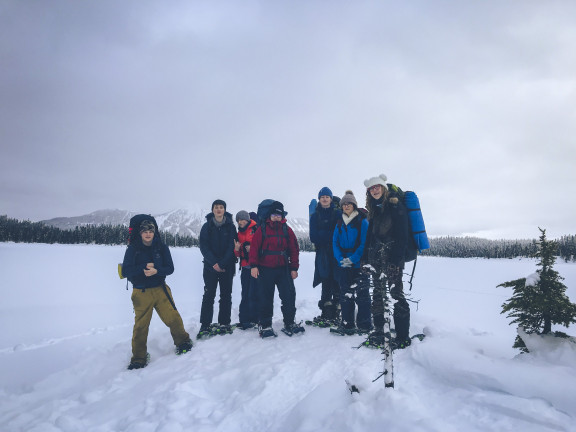 Students smiling in front of a snowy mountain