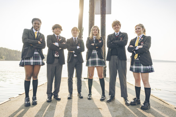 Six boarding students crossing their arms while posing on the docks