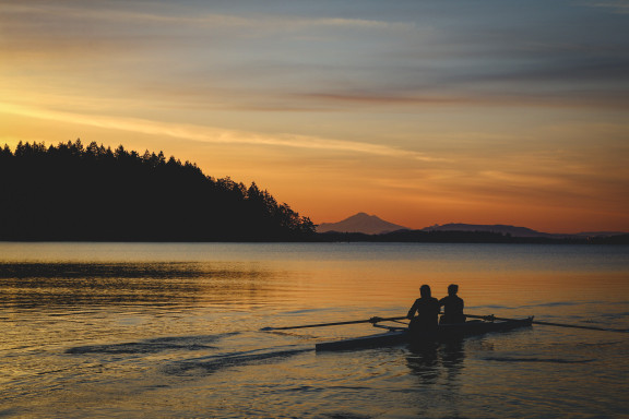 A sunrise with a pair of rowers out on the water