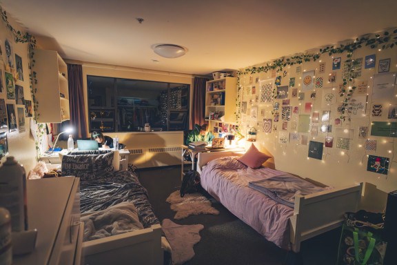 A dorm room in the evening with students working at their desks