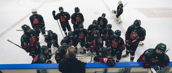 The Sr Hockey Team listening to the coach during intermission