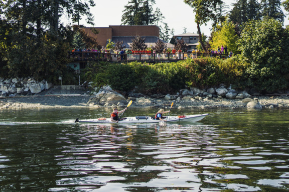 A kayak on the water in front of cheering students