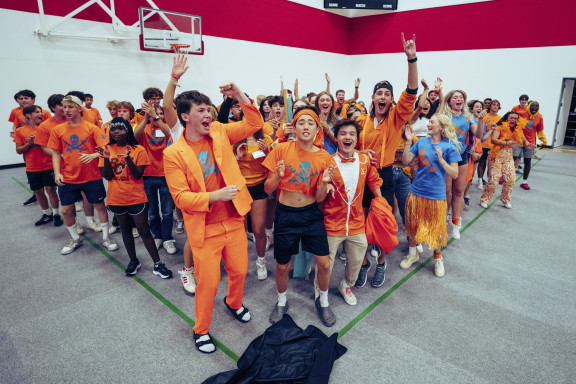 A group of students dressed in orange and blue cheering