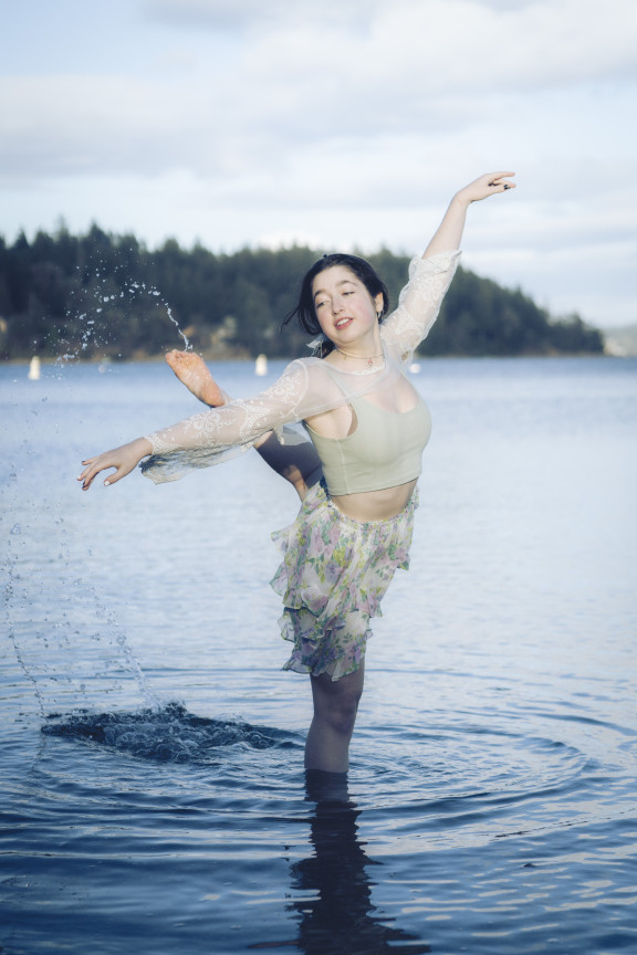 A dancer flicking water off their foot in the ocean