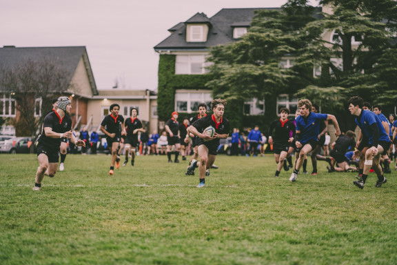 A boys rugby game showing a player running with the ball