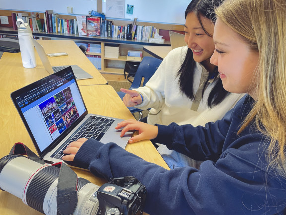 Students working on a laptop looking at the yearbook