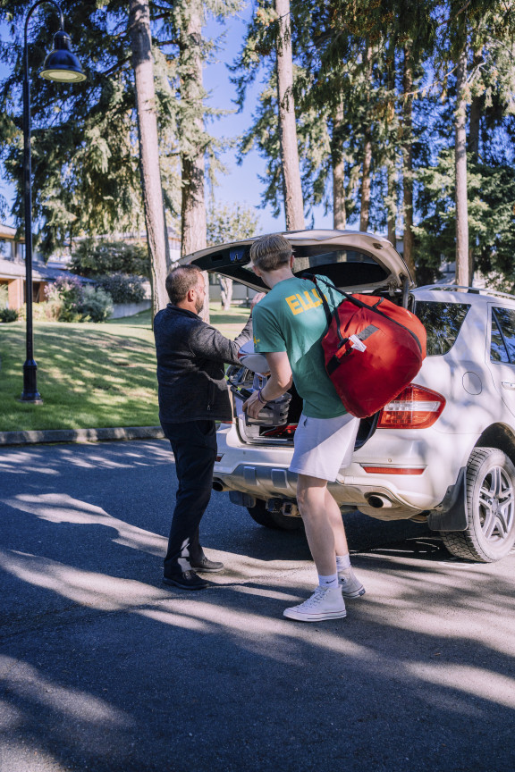 A new student unpacking luggage from the back of a car