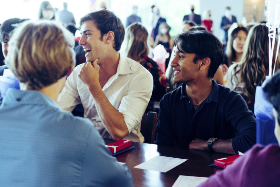 Students smiling while sitting down for a formal dinner