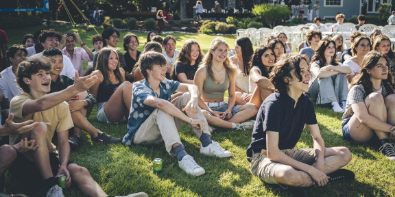 Students sitting outside smiling during a summer bbq