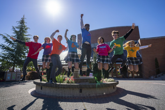 Eight students in their house colours jumping off the fountain