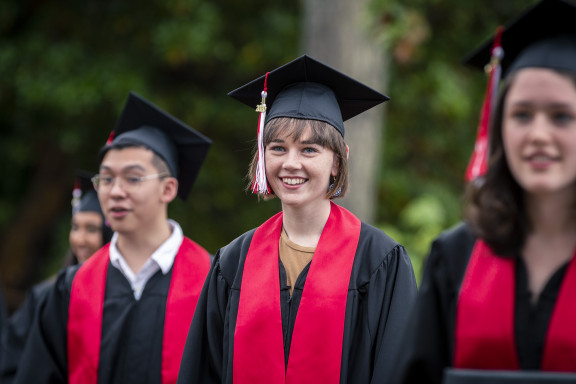 A student in cap and gown smiling