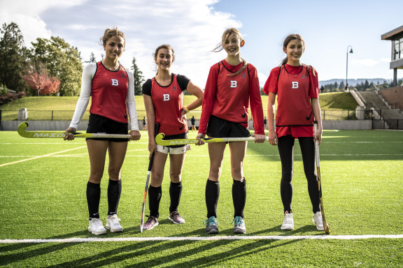 Field hockey players smiling while practicing on the turf field