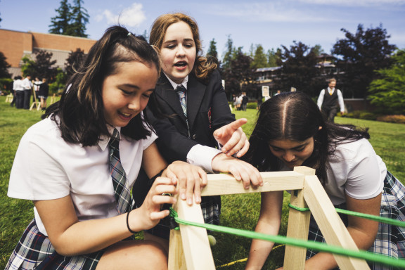 Three private school girls working on a science catapult