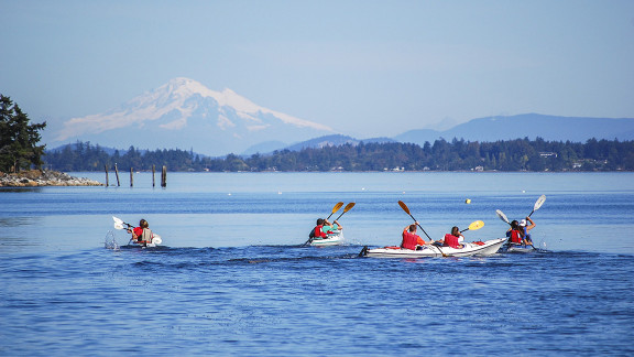 Student kayaking on the ocean towards Mount Baker