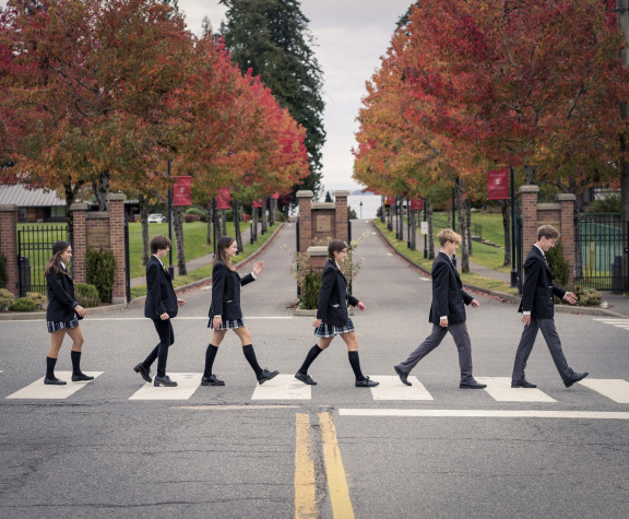 Students in uniform cross the street in front of the school