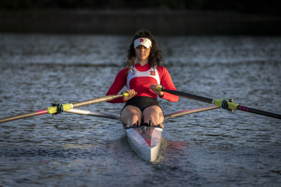 A student rowing in a single on the water