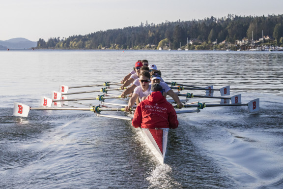 A group of rowers in an eight on the waters on Mill Bay