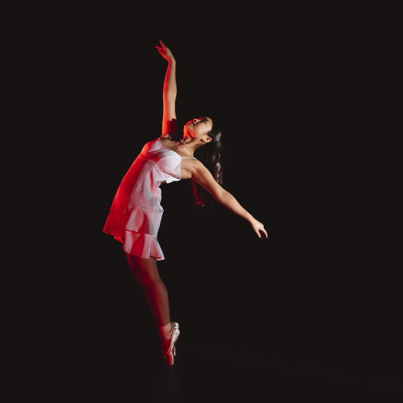 A dancer on stage in dramatic lighting