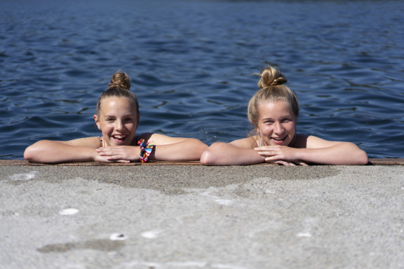 Two students smiling while swimming by the docks