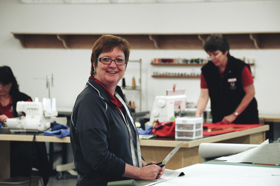 A laundry staff member smiling while working on some clothes alterations