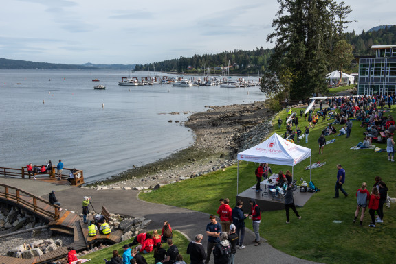 Regatta spectators with announcer tent and shells being carried to shore